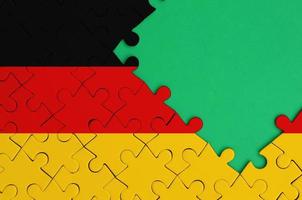 Germany flag  is depicted on a completed jigsaw puzzle with free green copy space on the right side photo