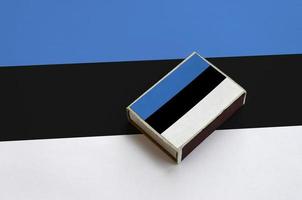 Estonia flag  is pictured on a matchbox that lies on a large flag photo