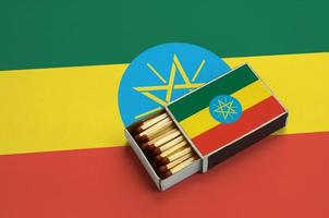 Ethiopia flag  is shown in an open matchbox, which is filled with matches and lies on a large flag photo
