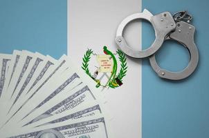 Guatemala flag  with handcuffs and a bundle of dollars. The concept of illegal banking operations in US currency photo