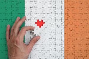 Ireland flag  is depicted on a puzzle, which the man's hand completes to fold photo