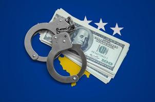 Kosovo flag  with handcuffs and a bundle of dollars. Currency corruption in the country. Financial crimes photo