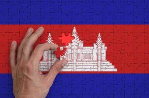 la bandera de camboya está representada en un rompecabezas, que la mano del hombre completa para doblar foto