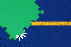 Nauru flag  is depicted on a completed jigsaw puzzle with free green copy space on the left side photo
