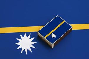 Nauru flag  is pictured on a matchbox that lies on a large flag photo