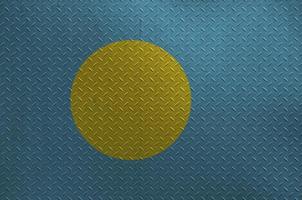 Palau flag depicted in paint colors on old brushed metal plate or wall closeup. Textured banner on rough background photo