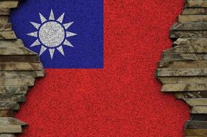 Taiwan flag depicted in paint colors on old stone wall closeup. Textured banner on rock wall background photo