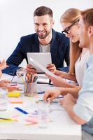 Working moments. Group of business people in smart casual wear sitting together at the table and smiling photo