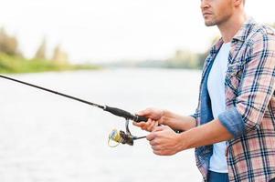 buen dia para pescar. confiado joven pescando mientras está de pie en el muelle foto