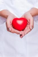 Taking good care of your heart. Close-up of female doctor in white uniform holding heart prop photo