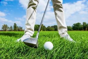 Teeing off. Close-up of male golfer teeing off while standing on golf course photo