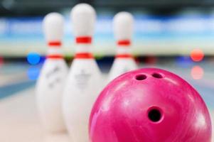 Bowling in details. Close-up of red bowling ball lying against pins staying on bowling alley photo