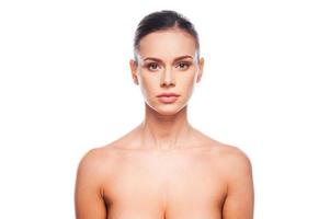 Natural as she is. Portrait of beautiful young shirtless woman looking at camera while standing against white background photo