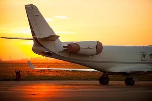 Ready to flight. Cropped image of airplane landing in airport with sunset in the background photo