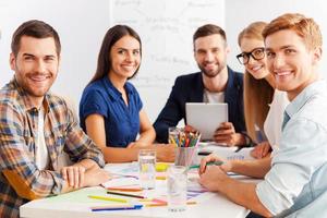 Working as team. Three confident business people in smart casual wear working together while sitting at the table photo