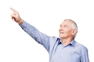 Look over there Happy senior man pointing away and smiling while standing against white background photo