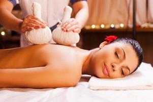 masaje para músculos cansados. Atractiva mujer joven acostada en el frente mientras el terapeuta de masaje le masajea la espalda foto