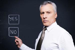 I would say no. Confident senior man in formalwear looking at camera and pointing chalk drawing on blackboard photo