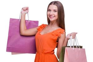 ventas hermosa mujer joven sosteniendo bolsas de compras y sonriendo mientras está de pie contra el fondo blanco foto