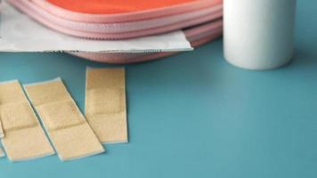 Slow pan of first aid supplies with adhesive bandages on blue green table surface