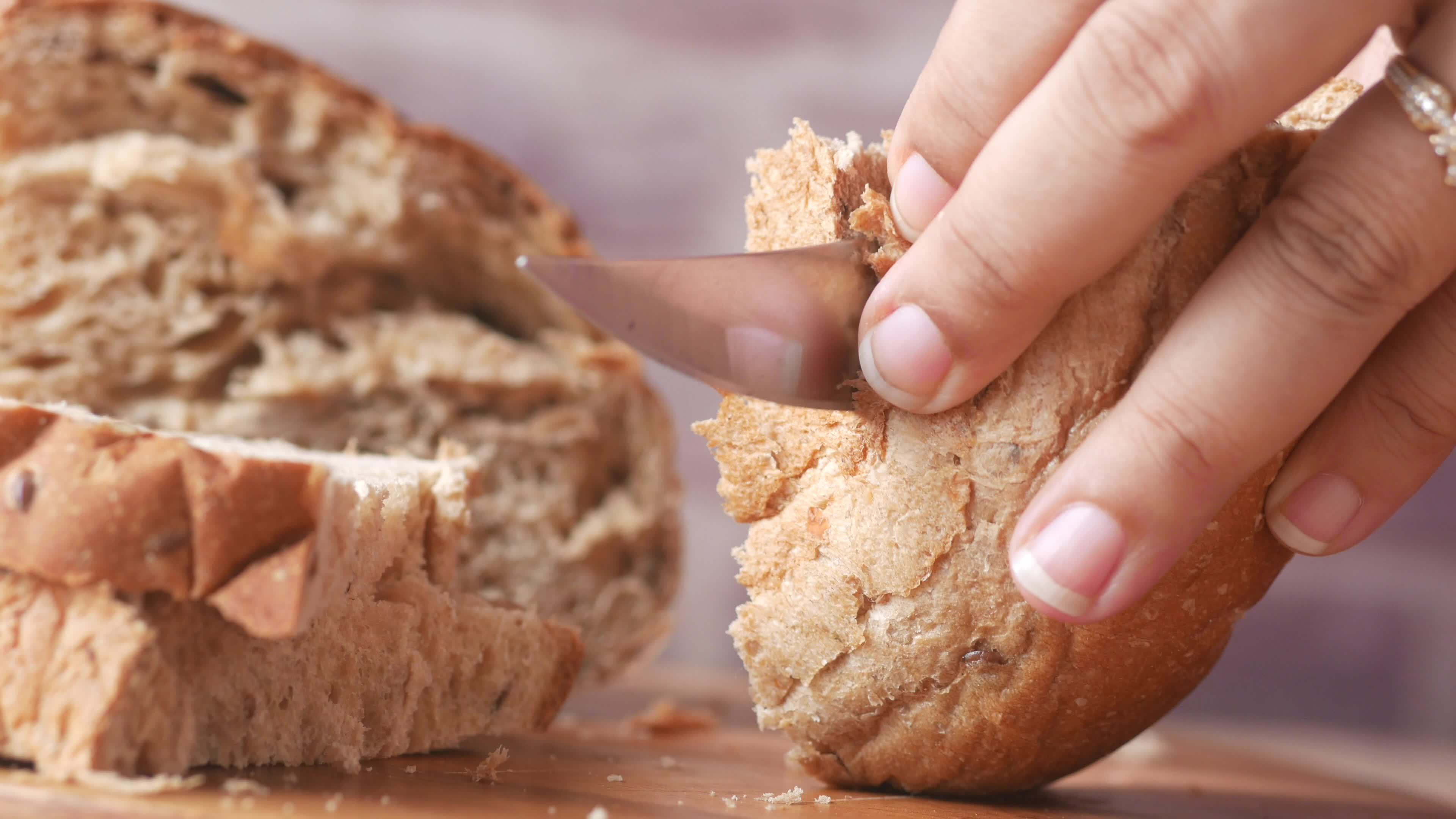 Slicing thick loaf of bread with a knife close up 13288197 Stock Video