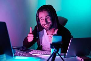 Happy young man looking at the computer monitor and gesturing against colorful background photo