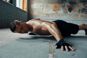 Handsome young man doing push-up exercises in gym photo