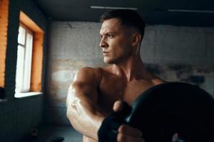 Handsome young man looking concentrated while doing weight training in gym photo