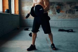 Unrecognizable muscular man training with dumbbell in gym photo