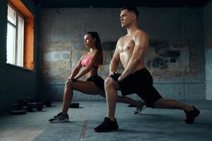 pareja en forma segura haciendo ejercicios de estiramiento en el gimnasio juntos foto