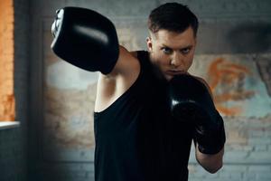 Handsome young man practicing in punching while standing in gym photo