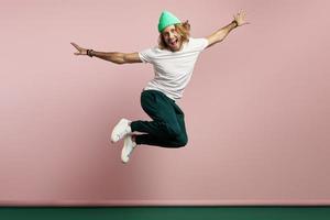 un joven apuesto que se ve feliz mientras salta contra un fondo colorido foto