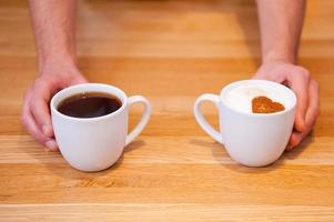 café recién hecho con amor. vista superior de primer plano del barista masculino que sirve dos tazas de café recién hecho para usted foto