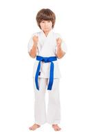 kárate. Niñito vestido uniforme de karate aislado en blanco foto