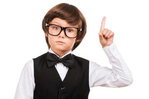 Look over there Cute little boy pointing up and looking at camera while standing isolated on white photo