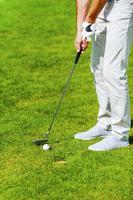 One shot to success. Close-up of man playing golf while standing on green and near the hole photo