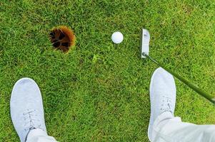 One shot to success. Top view of golfer putting while standing on green and near the hole photo