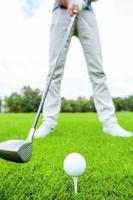 Teeing off. Close-up of golfer teeing off while standing on golf course photo