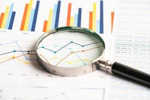 Magnifying glass on chart graph spreadsheet paper. Financial development, Banking Account, Statistics, economy, Stock exchange trading, Business office company meeting concept. photo