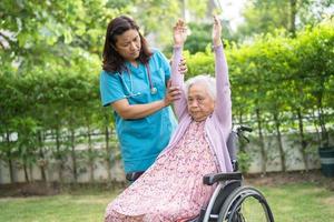 Doctor help Asian senior or elderly old lady woman patient exercise on wheelchair with happy in park. photo