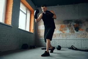 Fit young man practicing in punching while standing in gym photo