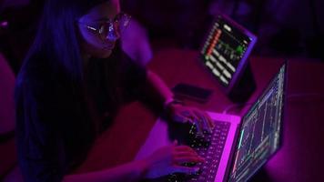 mujer joven en una habitación de color púrpura oscuro usa una computadora portátil video