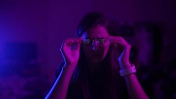 Young woman in a dark purple room uses a laptop video