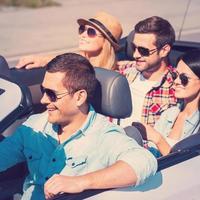 Traveling with fun. Top view of young happy people enjoying road trip in their white convertible photo