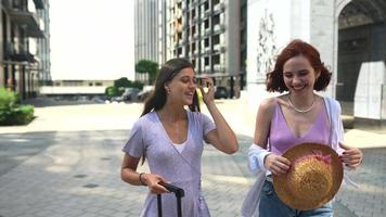 Two women with luggage outside talk and explore video