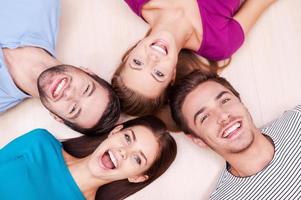 Happy together. Cheerful friends lying down and looking at camera photo