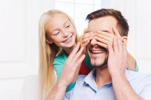 Guess who Playful little girl covering eyes of her cheerful mother and smiling photo