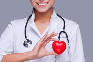 enamorada de su profesión. primer plano de una doctora en uniforme blanco sosteniendo un corazón y sonriendo foto