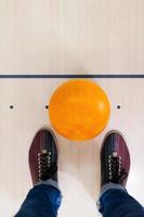 Ready for a game. Close-up of a bowling ball lying near human legs photo