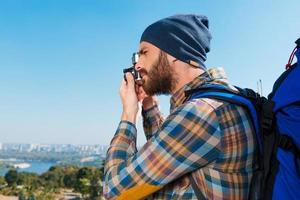 capturando recuerdos. un joven apuesto que lleva una mochila y toma una foto de una vista